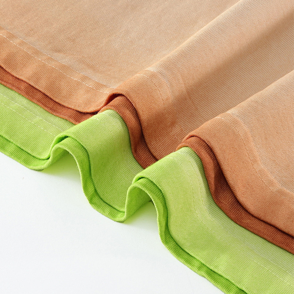 Folded washed cotton fabric in apricot and lime green, close-up