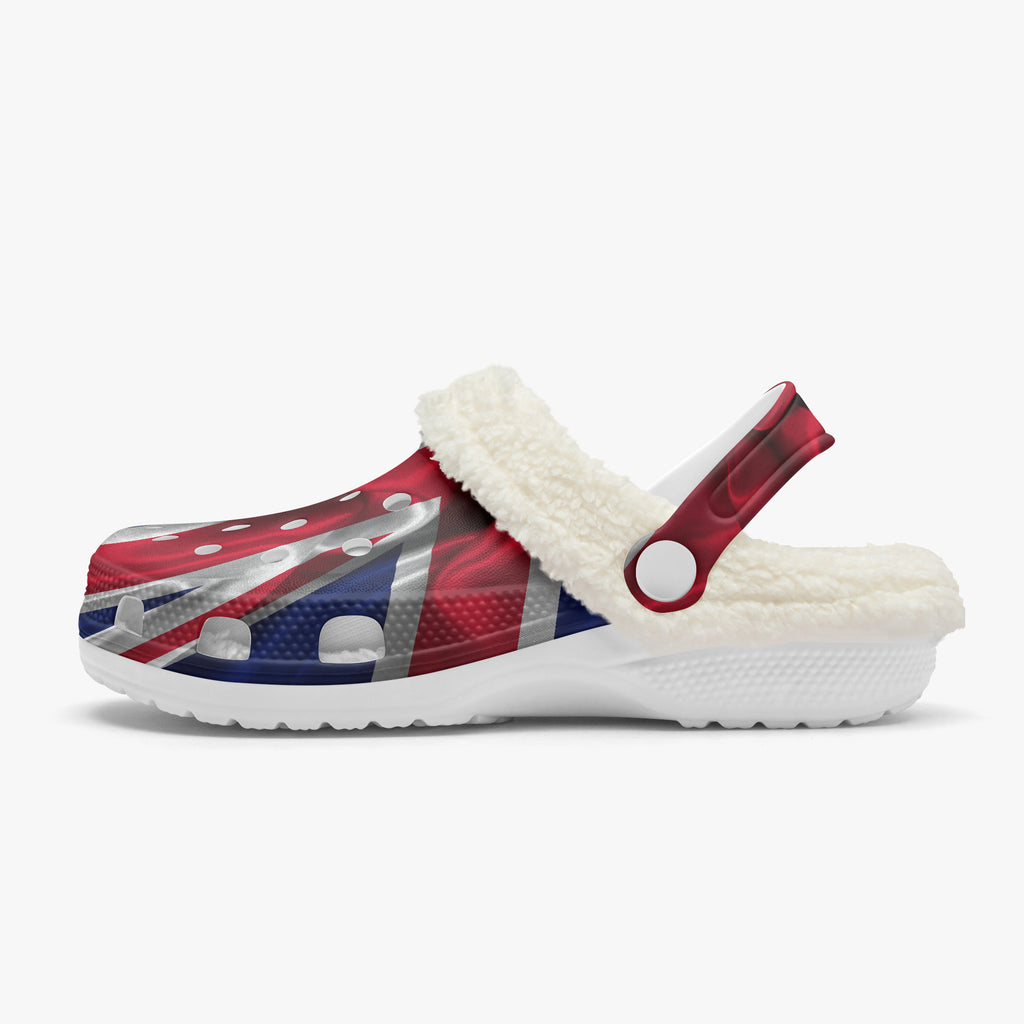 A single Croc-style clog shoe with a white sherpa lining and a strap, featuring a red, white, and blue Union Jack flag pattern on the upper, shown against a light gray background.