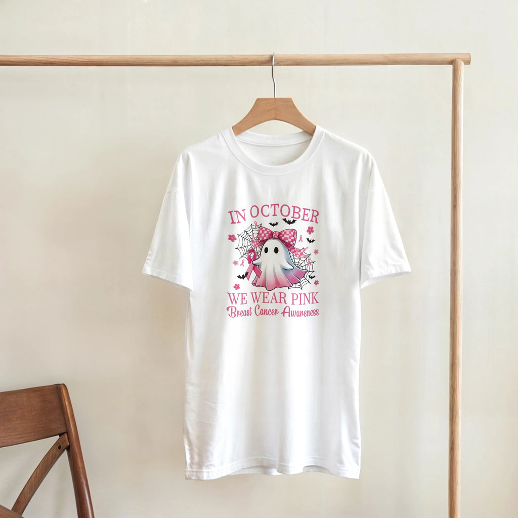 White unisex T-shirt with pink “IN OCTOBER” and “WE WEAR PINK” ghost graphic