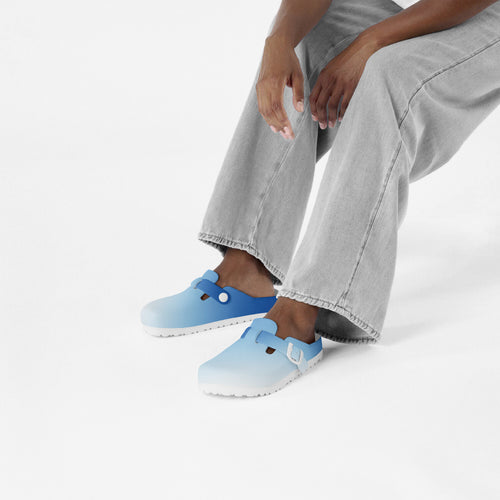 Light blue EVA slip-on clogs on feet with short jeans and socks