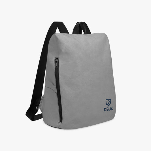 Light gray canvas backpack with black shoulder straps and front zip pocket, DBUK logo