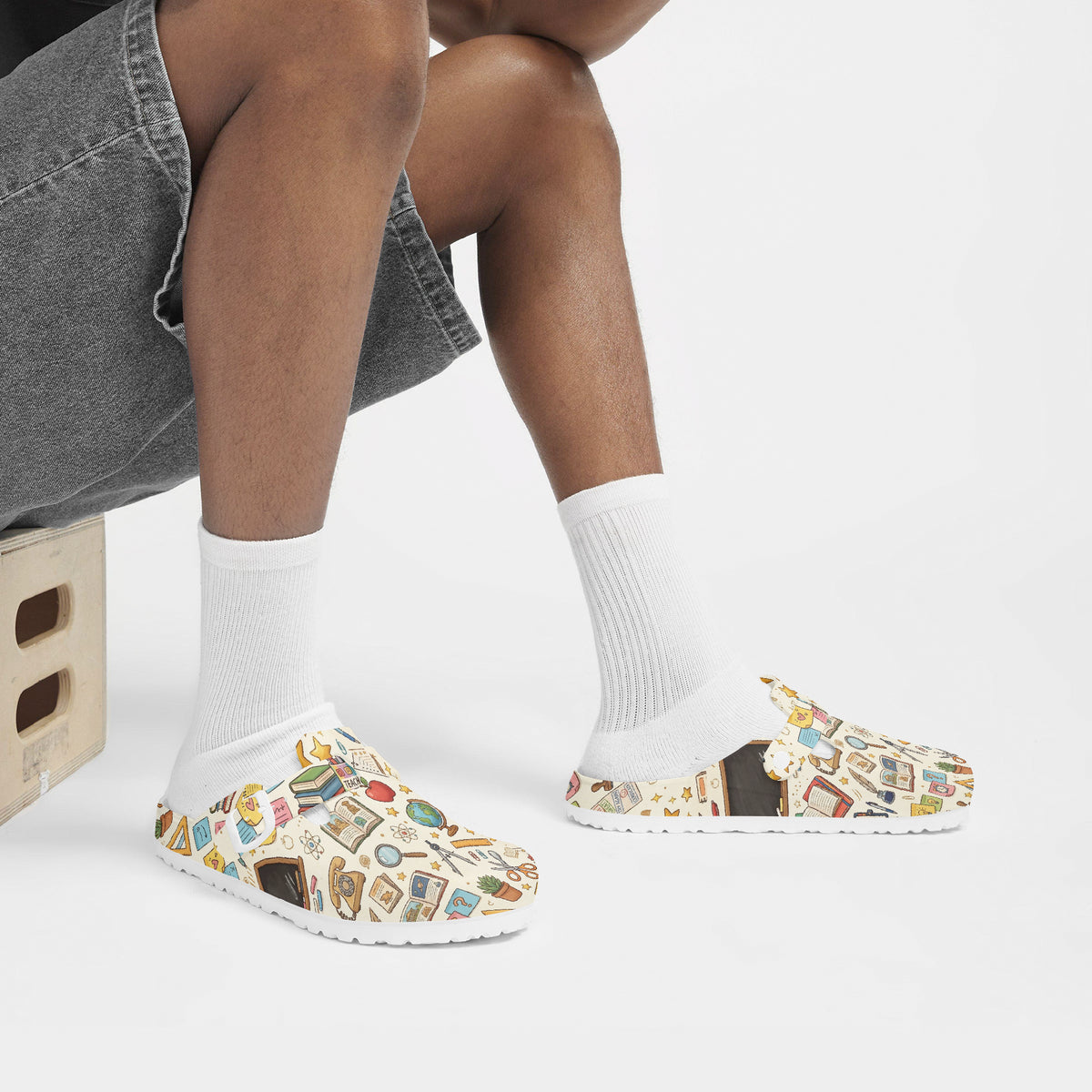 Slip-on clogs on white socks, white uppers with colorful classroom pattern