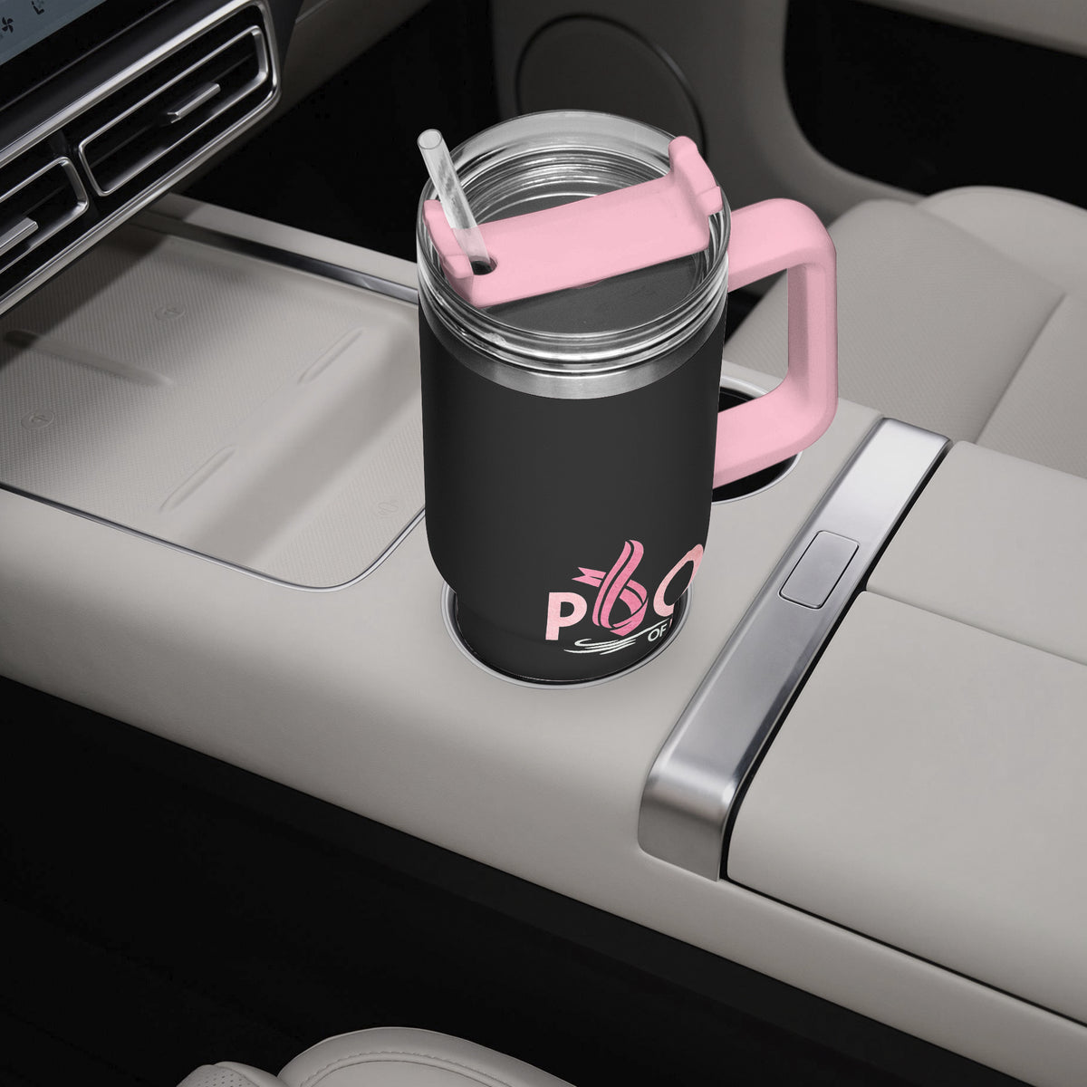 A black insulated travel tumbler cup with a pink handle, lid, and straw, featuring a pink 'Pool of Life' logo, shown in a car cup holder.