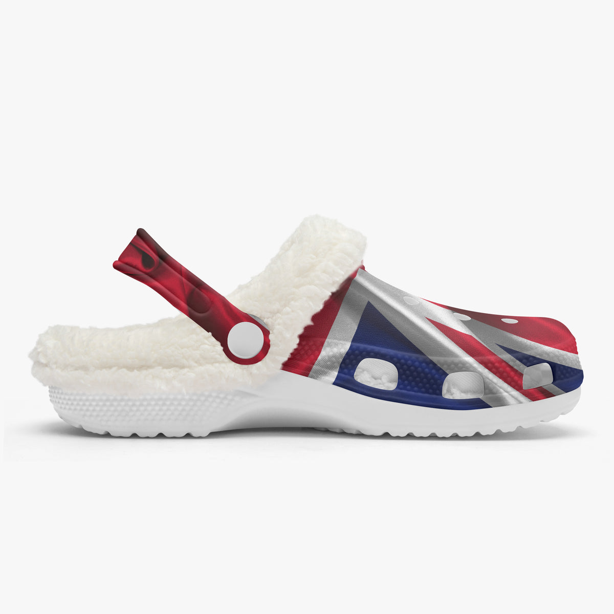 A white Croc-style clog shoe with a white sherpa lining and a strap, decorated with a Union Jack flag pattern in red, white, and blue on the upper, shown against a light gray background.