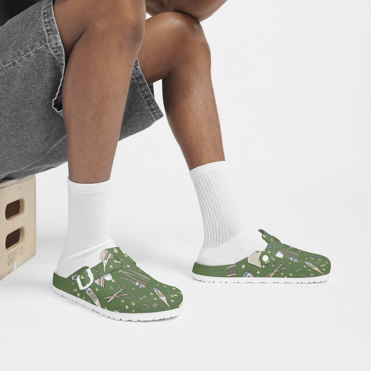 Green veterinary print EVA clogs on feet with white socks, slip-on style