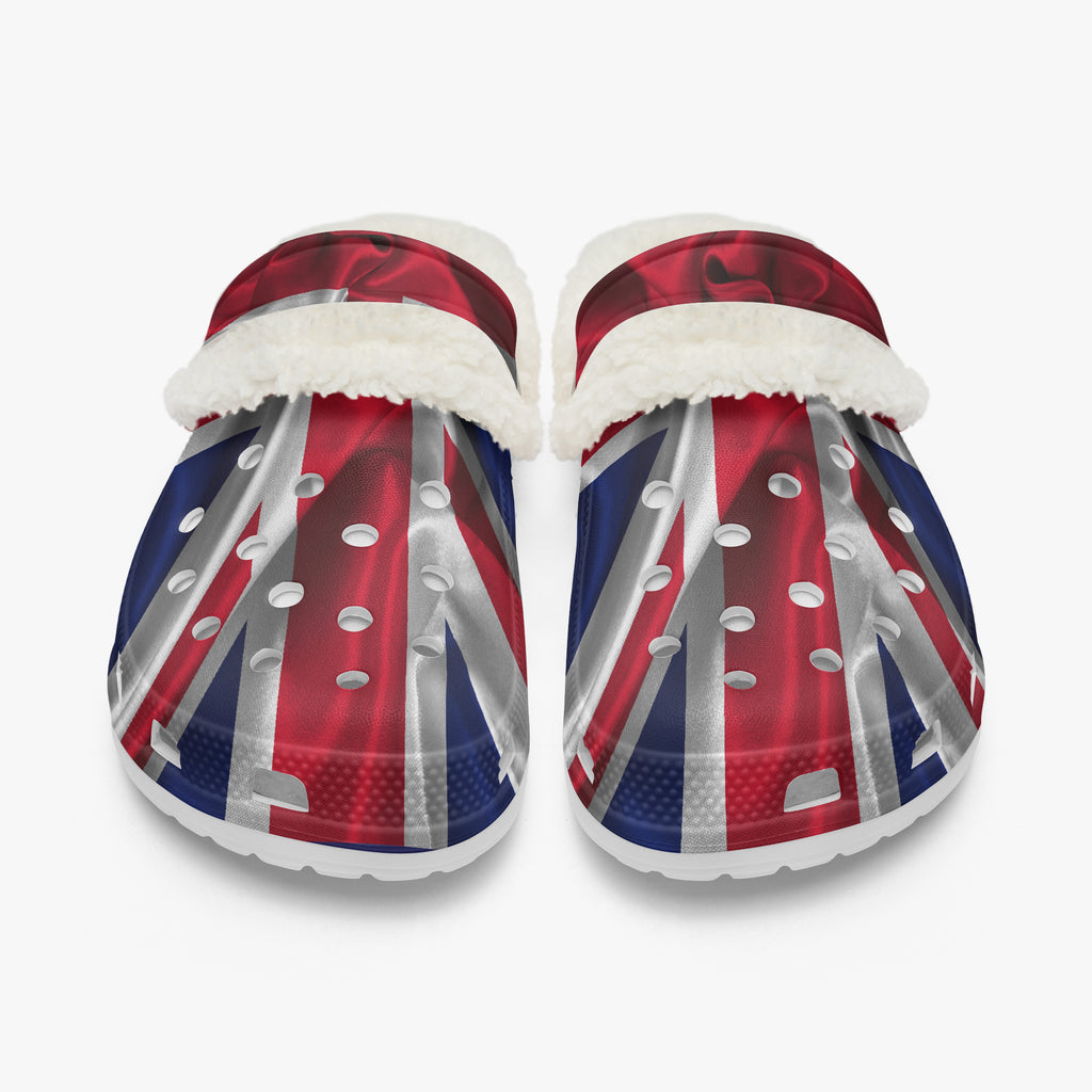A pair of clog-style slippers with a Union Jack flag print and white faux-fur trim, shown on a light gray background.