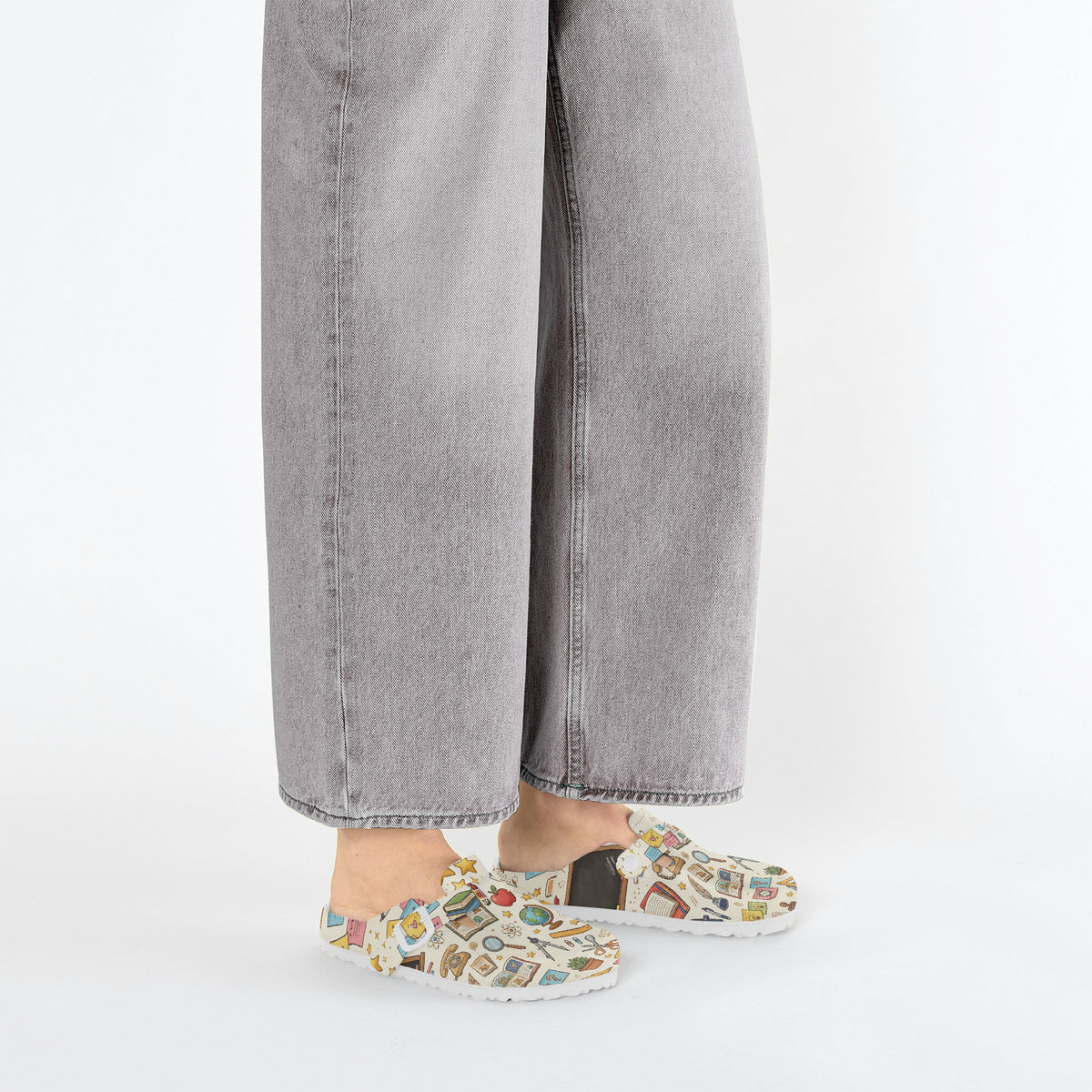 Close side view of slip-on clogs with white upper and colorful classroom icons