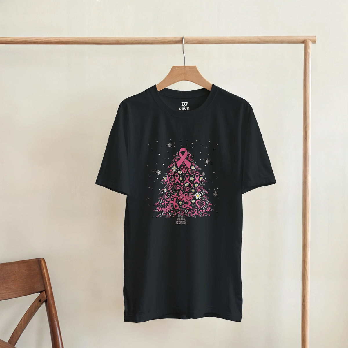 Black tee shirt with pink ribbon Christmas tree graphic displayed on a hanger
