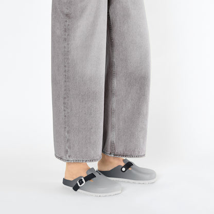 Grey slip-on clogs with black strap buckles under cuffed denim and white socks