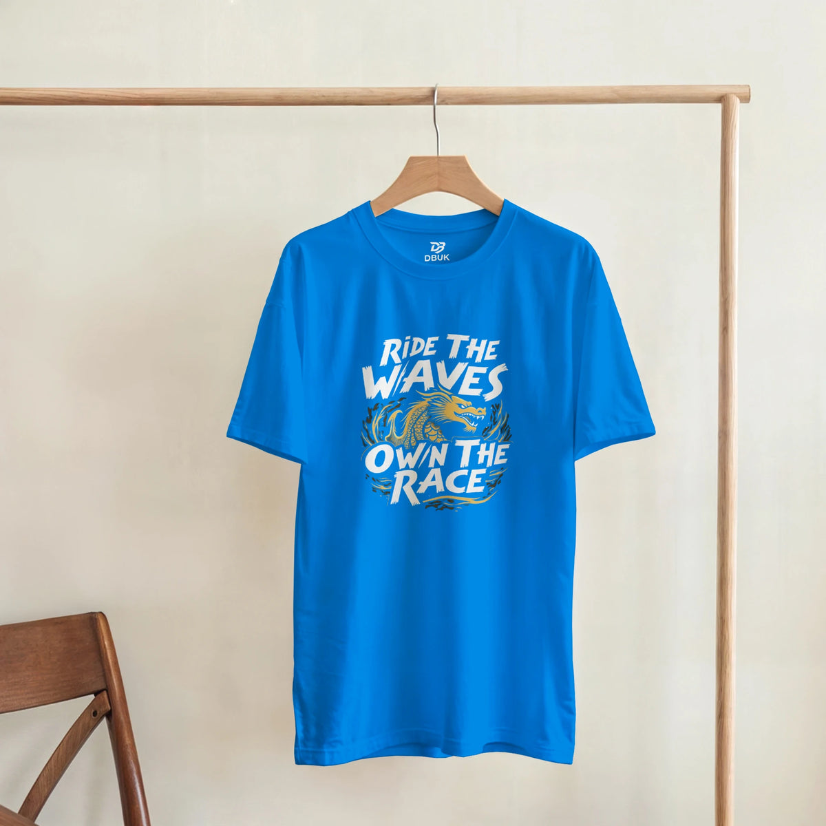 Unisex blue T-shirt with “Ride the Waves / Own the Race” dragon graphic, hanging