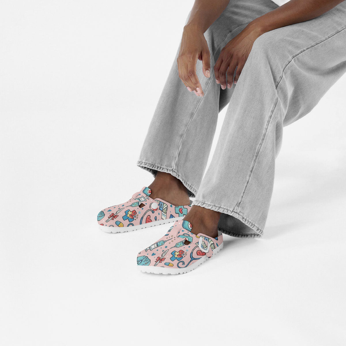 Person wearing pink medical doodle clogs with colorful cartoon print and white sole