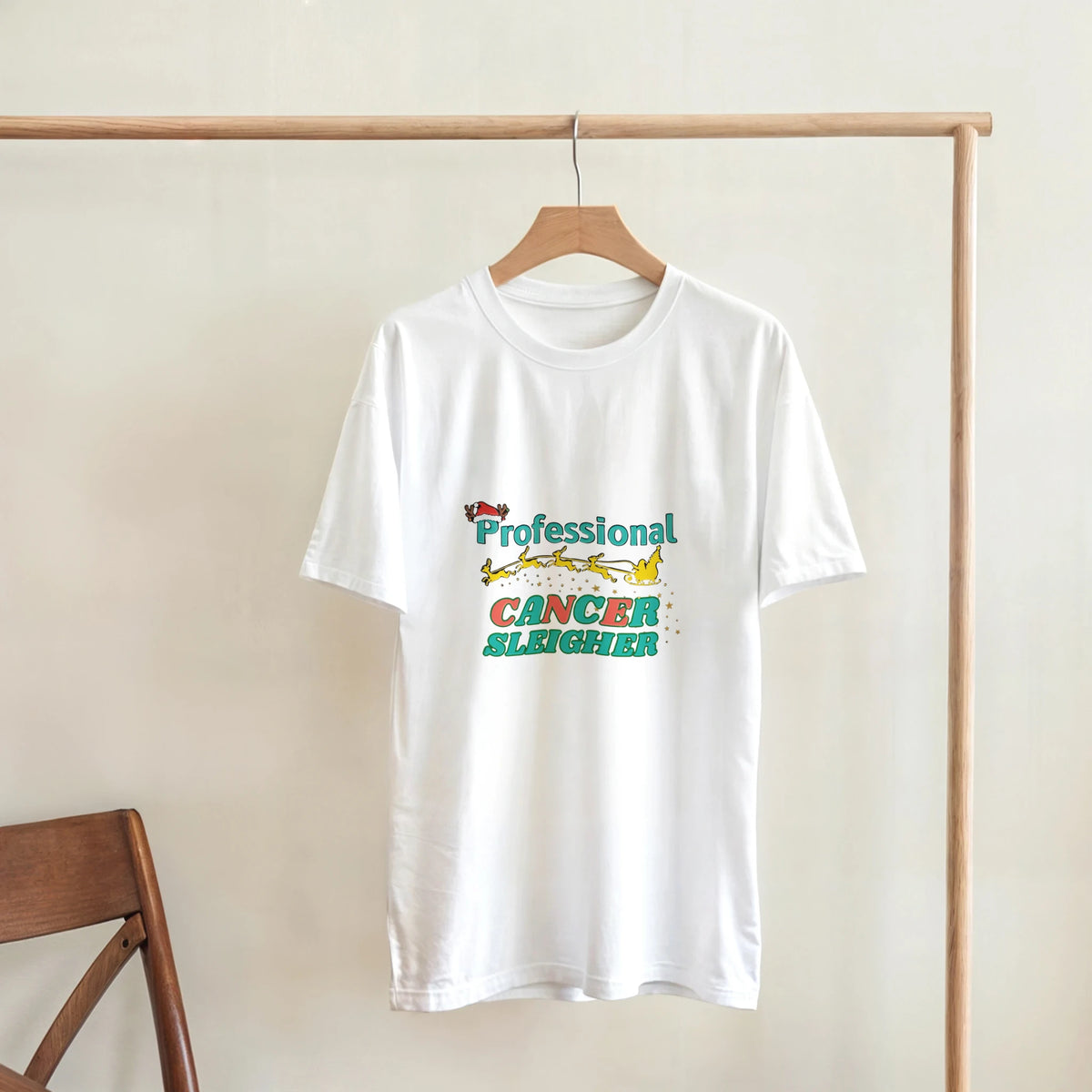 White crew neck T-shirt with colorful Cancer Sleigher graphic, on a wooden hanger