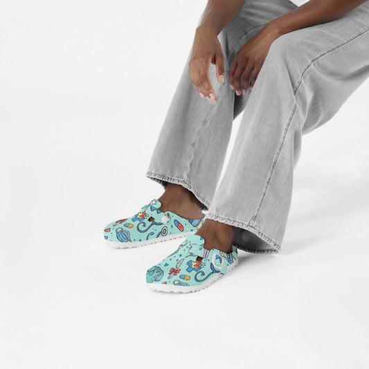 Light blue doodle medical clogs worn with gray pants; slip-on style