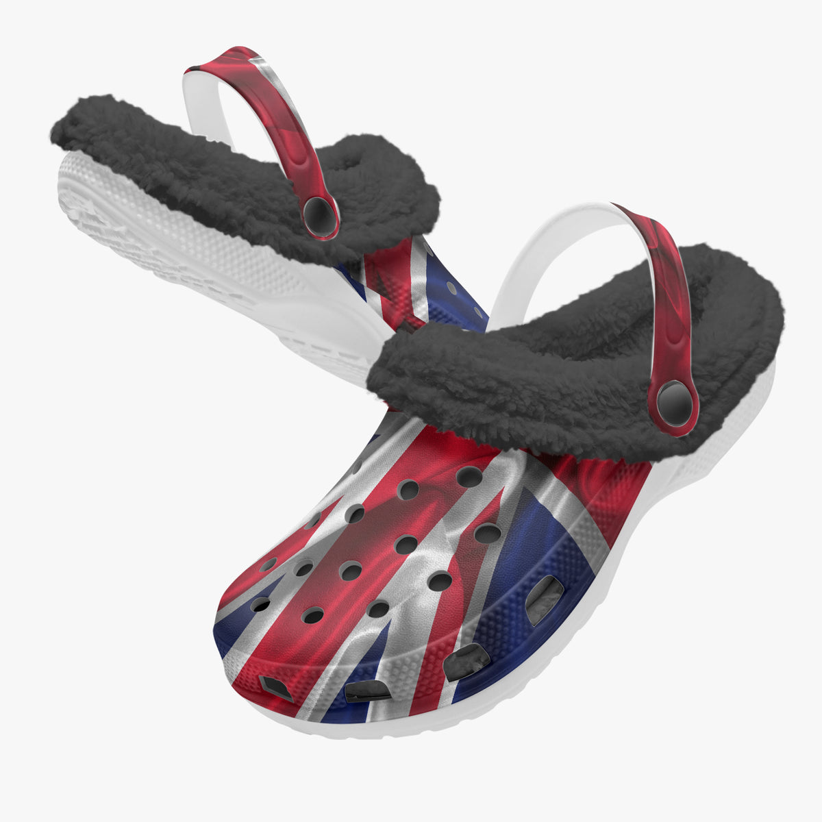 A pair of clog-style sandals with a Union Jack flag print on the upper, black sherpa lining, and red strap accents, shown on a plain light gray background.